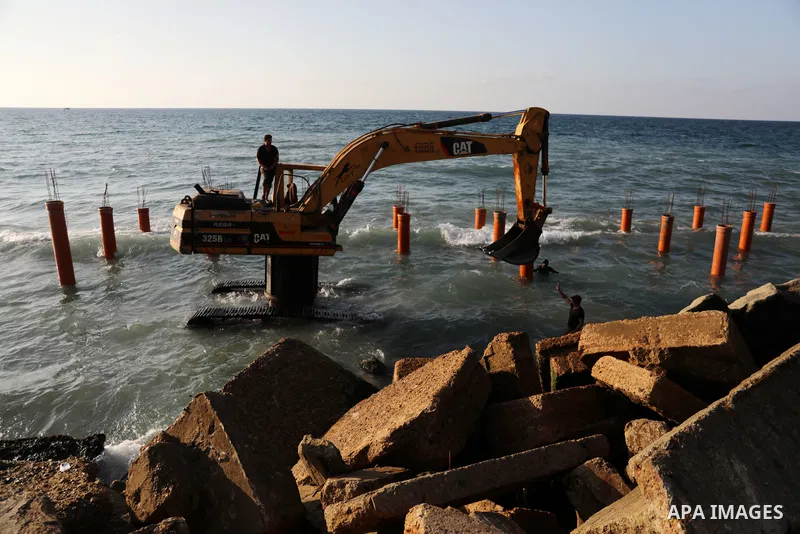 Palestinian workers operate a bulldozer to set up stilts in the Mediterranean sea to build a coffee shop at the Gaza city beach, using simple materials availabe in the besieged Gaza Strip, on October 27, 2021. Photo by M...