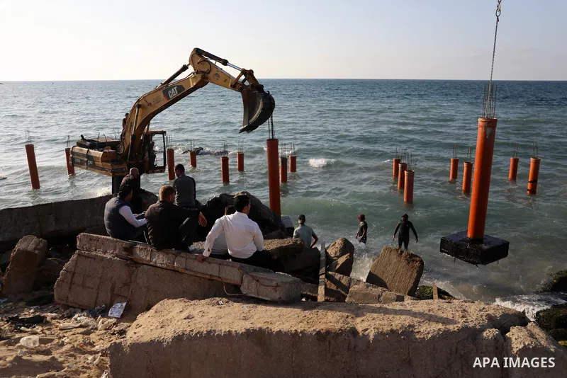 Palestinian workers operate a bulldozer to set up stilts in the Mediterranean sea to build a coffee shop at the Gaza city beach, using simple materials availabe in the besieged Gaza Strip, on October 27, 2021. Photo by M...