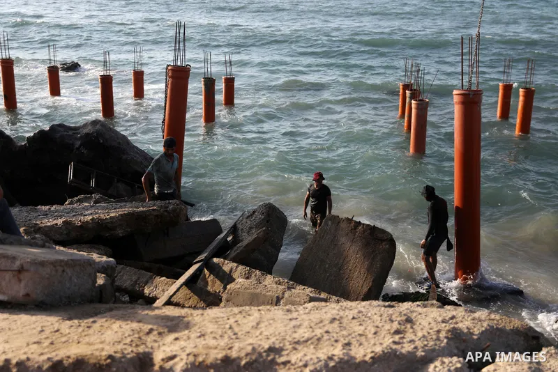 Palestinian workers operate a bulldozer to set up stilts in the Mediterranean sea to build a coffee shop at the Gaza city beach, using simple materials availabe in the besieged Gaza Strip, on October 27, 2021. Photo by M...