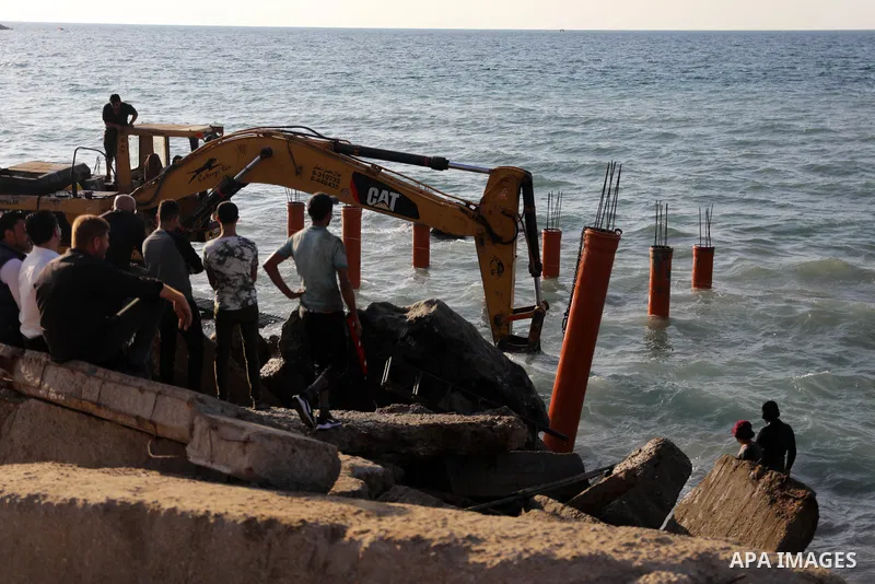 Palestinian workers operate a bulldozer to set up stilts in the Mediterranean sea to build a coffee shop at the Gaza city beach, using simple materials availabe in the besieged Gaza Strip, on October 27, 2021. Photo by M...