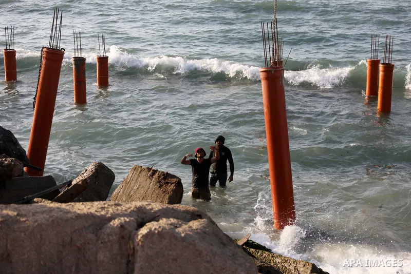 Palestinian workers operate a bulldozer to set up stilts in the Mediterranean sea to build a coffee shop at the Gaza city beach, using simple materials availabe in the besieged Gaza Strip, on October 27, 2021. Photo by M...