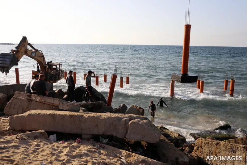 Palestinian workers operate a bulldozer to set up stilts in the Mediterranean sea to build a coffee shop at the Gaza city beach, using simple materials availabe in the besieged Gaza Strip, on October 27, 2021. Photo by M...