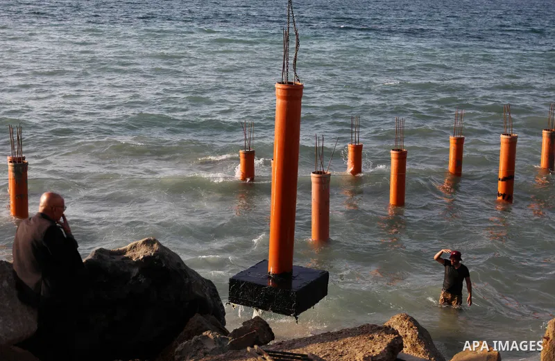 Palestinian workers operate a bulldozer to set up stilts in the Mediterranean sea to build a coffee shop at the Gaza city beach, using simple materials availabe in the besieged Gaza Strip, on October 27, 2021. Photo by M...