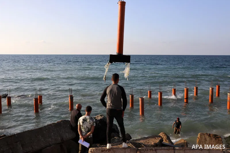 Palestinian workers operate a bulldozer to set up stilts in the Mediterranean sea to build a coffee shop at the Gaza city beach, using simple materials availabe in the besieged Gaza Strip, on October 27, 2021. Photo by M...