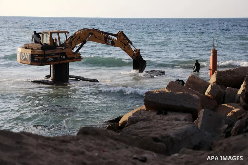 Palestinian workers operate a bulldozer to set up stilts in the Mediterranean sea to build a coffee shop at the Gaza city beach, using simple materials availabe in the besieged Gaza Strip, on October 27, 2021. Photo by M...