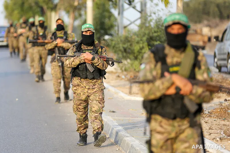 Masked militants from the Izzedine al-Qassam Brigades, a military wing of Hamas, march with their rifles along the main road of Nusseirat refugee camp, central Gaza Strip, in solidarity with Palestinian prisoners on hung...