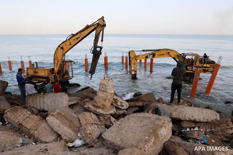 Palestinian workers operate a bulldozer to set up stilts in the Mediterranean sea to build a coffee shop at the Gaza city beach, using simple materials availabe in the besieged Gaza Strip, on October 27, 2021. Photo by M...