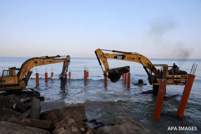 Palestinian workers operate a bulldozer to set up stilts in the Mediterranean sea to build a coffee shop at the Gaza city beach, using simple materials availabe in the besieged Gaza Strip, on October 27, 2021. Photo by M...