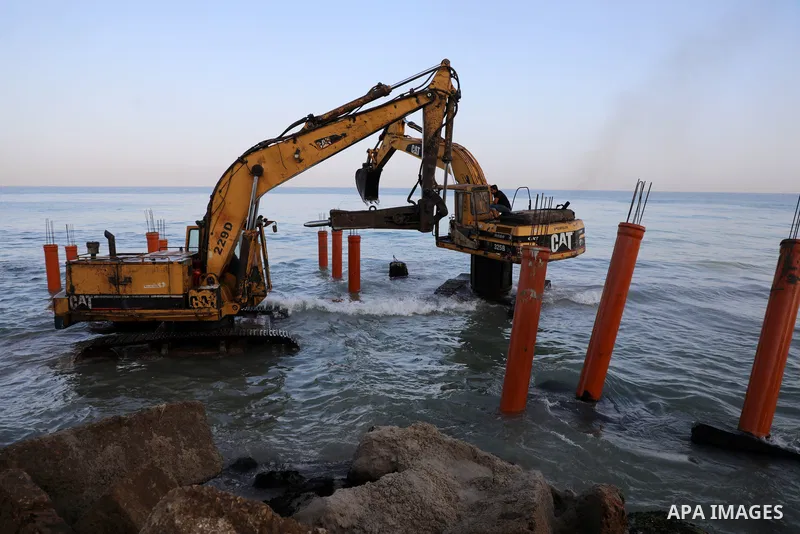 Palestinian workers operate a bulldozer to set up stilts in the Mediterranean sea to build a coffee shop at the Gaza city beach, using simple materials availabe in the besieged Gaza Strip, on October 27, 2021. Photo by M...