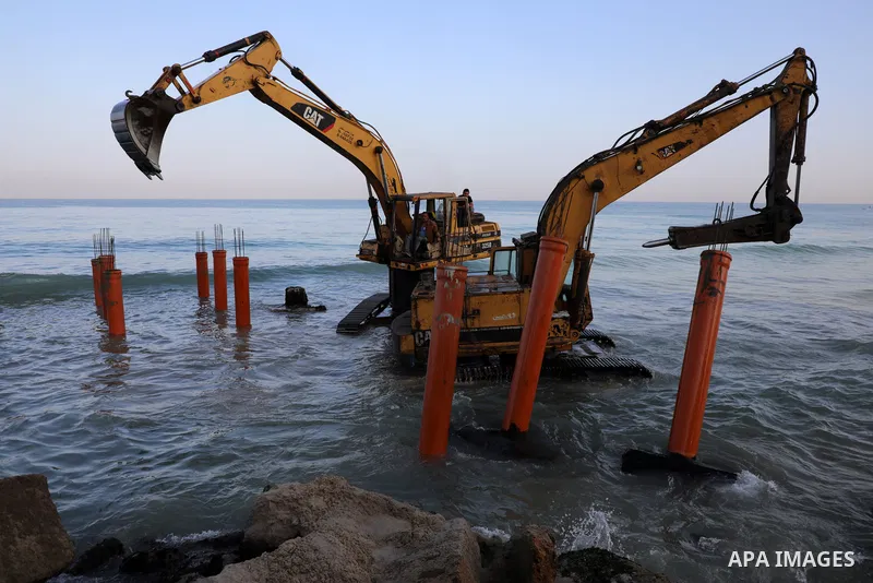 Palestinian workers operate a bulldozer to set up stilts in the Mediterranean sea to build a coffee shop at the Gaza city beach, using simple materials availabe in the besieged Gaza Strip, on October 27, 2021. Photo by M...