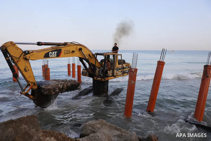 Palestinian workers operate a bulldozer to set up stilts in the Mediterranean sea to build a coffee shop at the Gaza city beach, using simple materials availabe in the besieged Gaza Strip, on October 27, 2021. Photo by M...