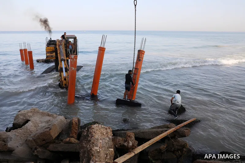Palestinian workers operate a bulldozer to set up stilts in the Mediterranean sea to build a coffee shop at the Gaza city beach, using simple materials availabe in the besieged Gaza Strip, on October 27, 2021. Photo by M...