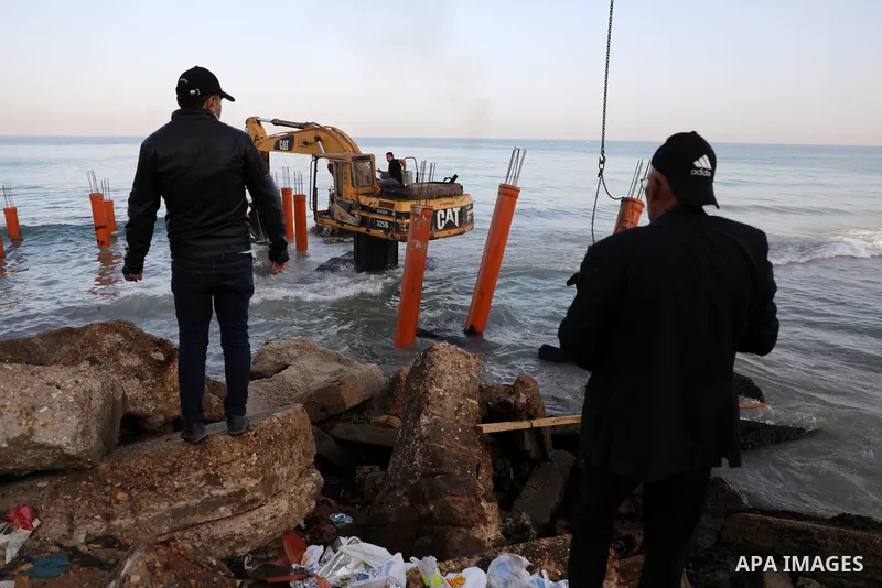 Palestinian workers operate a bulldozer to set up stilts in the Mediterranean sea to build a coffee shop at the Gaza city beach, using simple materials availabe in the besieged Gaza Strip, on October 27, 2021. Photo by M...
