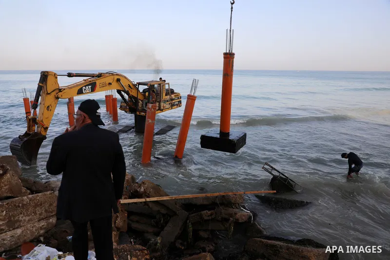 Palestinian workers operate a bulldozer to set up stilts in the Mediterranean sea to build a coffee shop at the Gaza city beach, using simple materials availabe in the besieged Gaza Strip, on October 27, 2021. Photo by M...