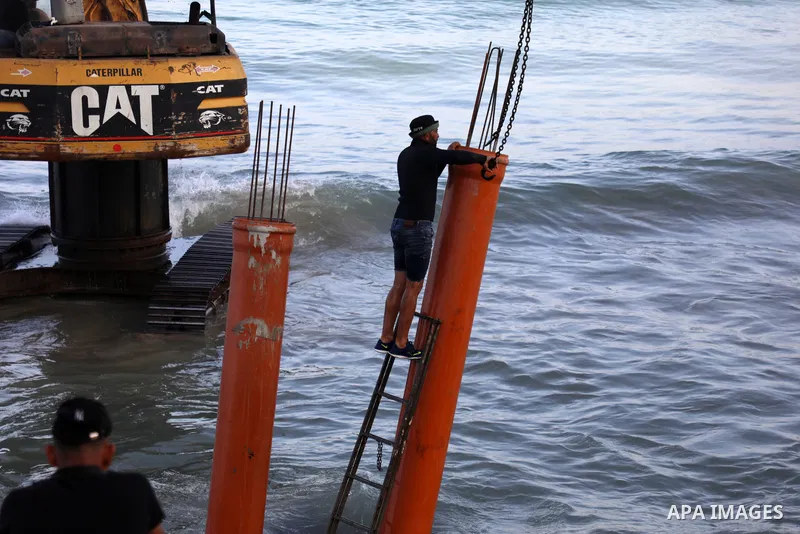 Palestinian workers operate a bulldozer to set up stilts in the Mediterranean sea to build a coffee shop at the Gaza city beach, using simple materials availabe in the besieged Gaza Strip, on October 27, 2021. Photo by M...