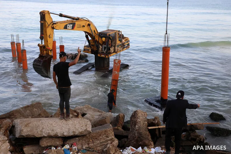 Palestinian workers operate a bulldozer to set up stilts in the Mediterranean sea to build a coffee shop at the Gaza city beach, using simple materials availabe in the besieged Gaza Strip, on October 27, 2021. Photo by M...