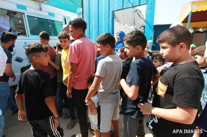 Palestinian volunteers distribute ice cream for free to children in Al-Shati refugee camp. 0.1