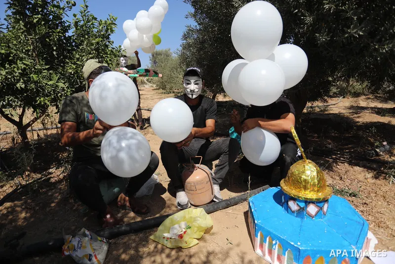 Masked Palestinians prepare incendiary balloons near Jabalia in the northern of Gaza Strip, on September 4, 2021. Reports in Palestinian media indicated that units in charge of incendiary balloon attacks on Israeli plann...