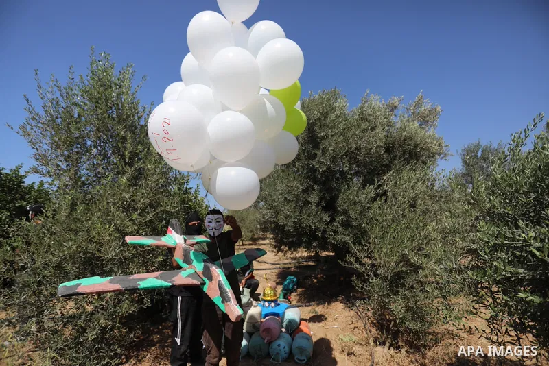 Masked Palestinians prepare incendiary balloons near Jabalia in the northern of Gaza Strip, on September 4, 2021. Reports in Palestinian media indicated that units in charge of incendiary balloon attacks on Israeli plann...