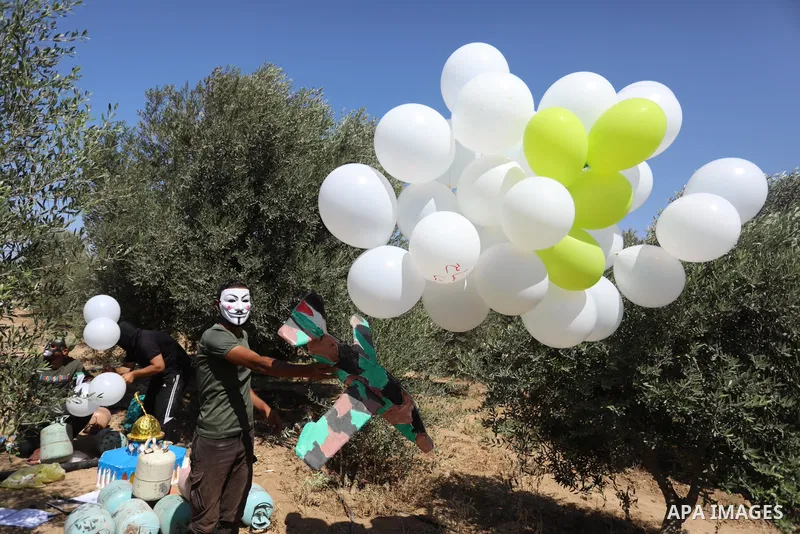 Masked Palestinians prepare incendiary balloons near Jabalia in the northern of Gaza Strip, on September 4, 2021. Reports in Palestinian media indicated that units in charge of incendiary balloon attacks on Israeli plann...