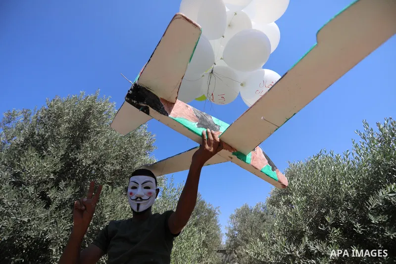 Masked Palestinians prepare incendiary balloons near Jabalia in the northern of Gaza Strip, on September 4, 2021. Reports in Palestinian media indicated that units in charge of incendiary balloon attacks on Israeli plann...