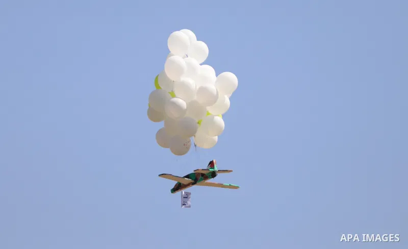Masked Palestinians prepare incendiary balloons near Jabalia in the northern of Gaza Strip, on September 4, 2021. Reports in Palestinian media indicated that units in charge of incendiary balloon attacks on Israeli plann...