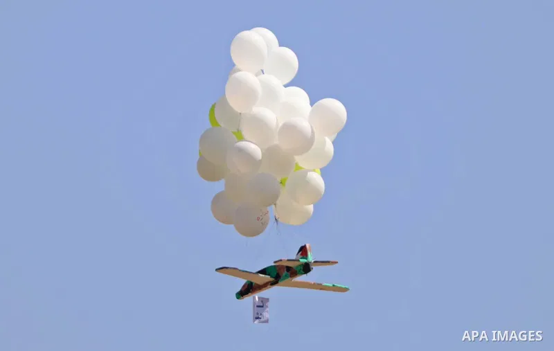 Masked Palestinians prepare incendiary balloons near Jabalia in the northern of Gaza Strip, on September 4, 2021. Reports in Palestinian media indicated that units in charge of incendiary balloon attacks on Israeli plann...