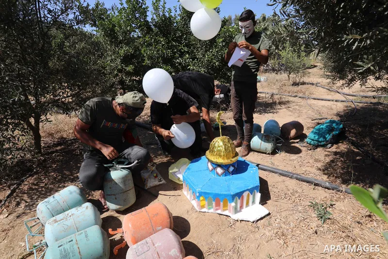 Masked Palestinians prepare incendiary balloons near Jabalia in the northern of Gaza Strip, on September 4, 2021. Reports in Palestinian media indicated that units in charge of incendiary balloon attacks on Israeli plann...