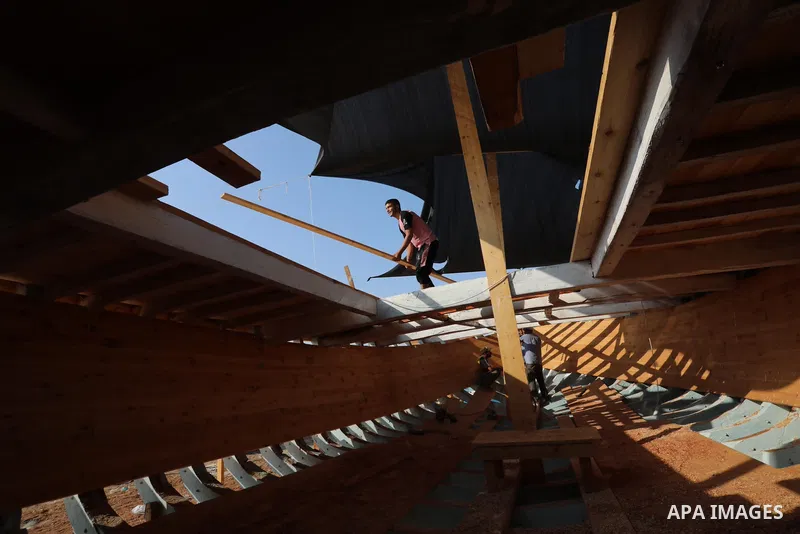 Palestinians work on the largest fishing boat in Khan Yunis in the southern of Gaza Strip, on September 5, 2021. Palestinians made the largest fishing boat in the Gaza Strip, 21 meters long and 6 meters wide, with simple...