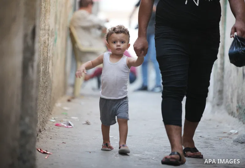 A Palestinian man and his son walk at a street in al-Shati refugee camp, west of Gaza City, on September 5, 2021. Over the last 14 years, Gaza residents have endured four deadly Israeli attacks, rebuilding after each one...
