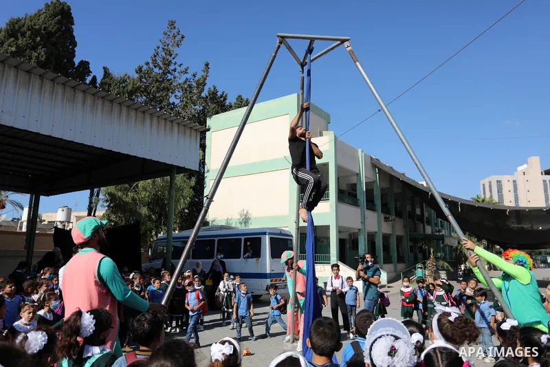 Palestinian students enjoy a circus performance, in Deir al-Balah in the center of Gaza Strip, on September 12, 2021. Members of Gaza stars circus school launched an initiative to entertain Palestinian children in margin...