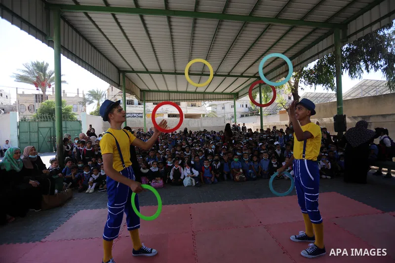 Palestinian students enjoy a circus performance, in Deir al-Balah in the center of Gaza Strip, on September 12, 2021. Members of Gaza stars circus school launched an initiative to entertain Palestinian children in margin...