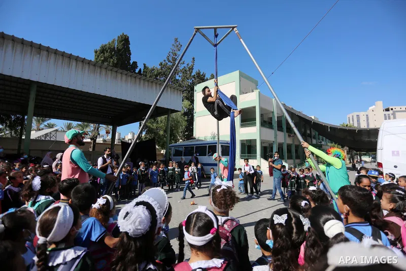 Palestinian students enjoy a circus performance, in Deir al-Balah in the center of Gaza Strip, on September 12, 2021. Members of Gaza stars circus school launched an initiative to entertain Palestinian children in margin...