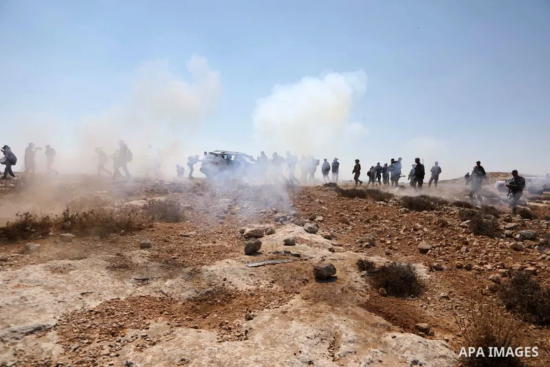 Palestinians and foreign activists run for cover from tear gas fired by Israeli soldiers during a demonstration against Israeli land confiscation and the cutting water supply for Palestinians villages, in the southern ar...