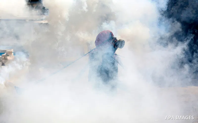 A Palestinian protester uses a slingshot to throw back a tear gaz towards Israeli security forces during clashes following a demonstration against settlements in the West Bank village of Beita, on September 17, 2021. Pho...