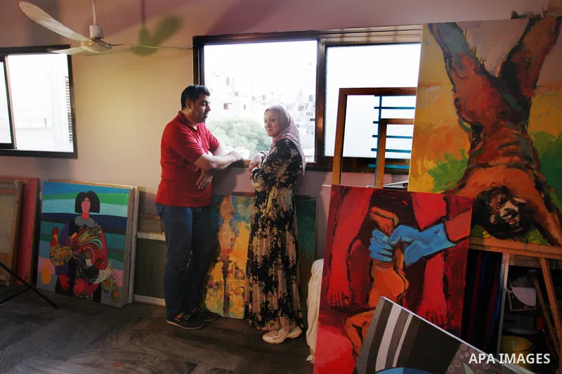 Palestinian plastic artists Mohammed Al-Hawajri and his wife Dina Matar set up an exhibition of their paintings on the roof of their house in Al-Bureij refugee camp in the center of Gaza strip, on August 28, 2021. The tw...