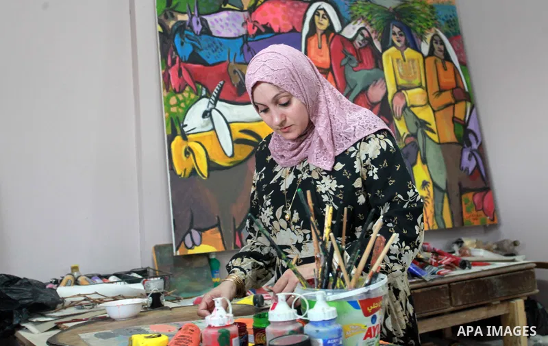 Palestinian plastic artists Mohammed Al-Hawajri and his wife Dina Matar set up an exhibition of their paintings on the roof of their house in Al-Bureij refugee camp in the center of Gaza strip, on August 28, 2021. The tw...