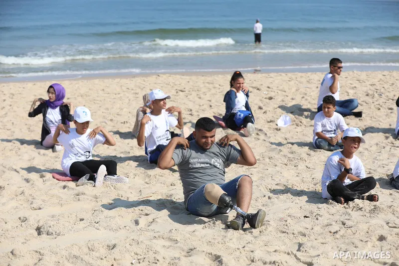 Palestinian children of special needs perform yoga, on a beach in Gaza City on August 2, 2021. The organization has launched on sunday the summer camp in the Middle East, which called "Camp Ability" for children with amp...