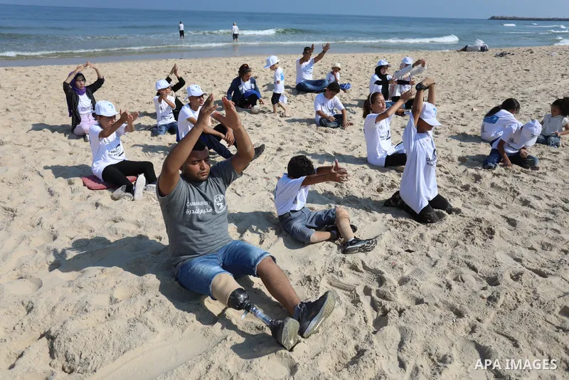 Palestinian children of special needs perform yoga, on a beach in Gaza City on August 2, 2021. The organization has launched on sunday the summer camp in the Middle East, which called "Camp Ability" for children with amp...