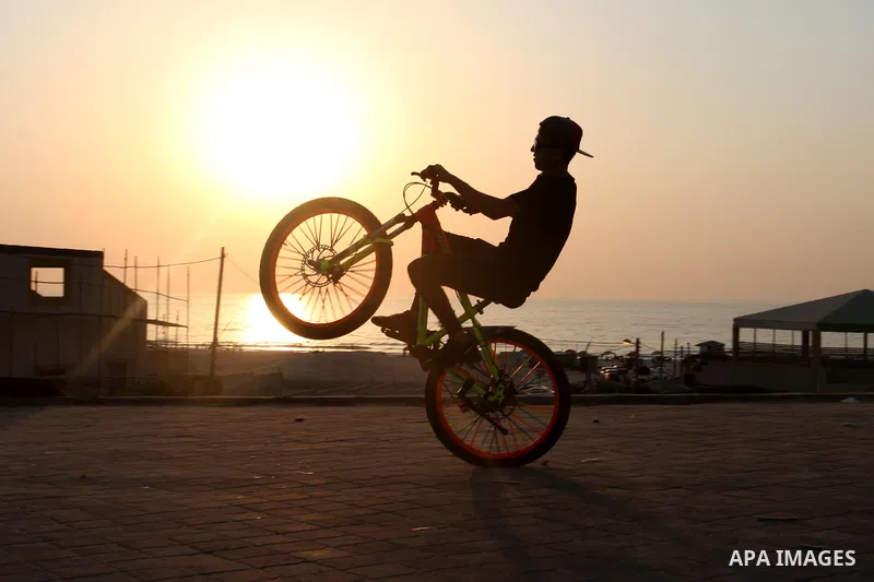 Palestinian youths show their skills while riding bicycles in Gaza city on August 6, 2021. Photo by Omar Ashtawy