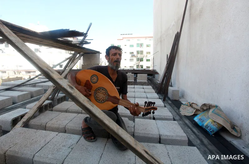 Palestinian refugee, Kamal Abu Ghabin, 57, plays the lute known in Arabic as an "Oud", during his rest, in Gaza city, on August 8, 2021. Abu Ghabin works as a blacksmith and has been playing the oud since his childhood....