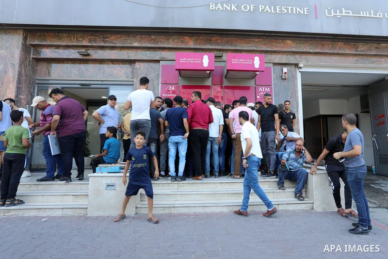 Palestinian Authority employees wait outside banks to receive their salaries, in Gaza city on August 10, 2021. Palestine is facing a financial crisis amid a decline in foreign aid and a growing tax dispute with Israel. T...