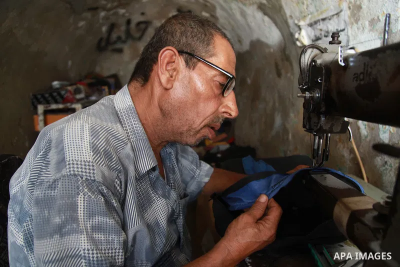 Palestinian tailor Khalil Hamdan, 64, ​re-sewing worn out shoes and bags for students before the start of the new school year, in light of difficult economic and living conditions for Gazans, at al-Zawya market in Gaza c...