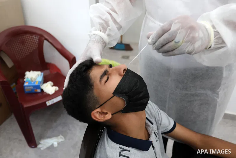A Palestinian health worker collects a swab sample from a person for Covid-19 test, at a temporary vaccination centre set up in Khan Younis in the southern Gaza Strip on August 23, 2021. Palestinian health officials on M...