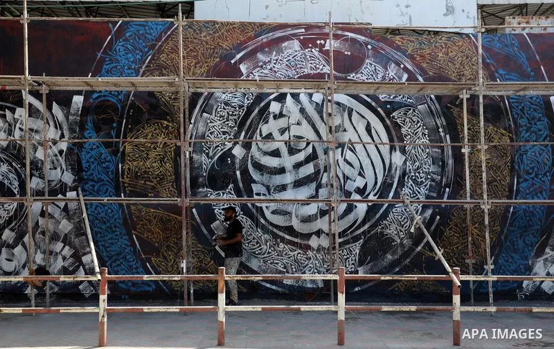 Palestinian artist Bilal Khaled draws on a wall ordinate in Gaza city on July 1, 2021. "Graffiti" (usually both singular and plural) and the rare singular form "graffito" are from the Italian word graffiato ("scratched")...