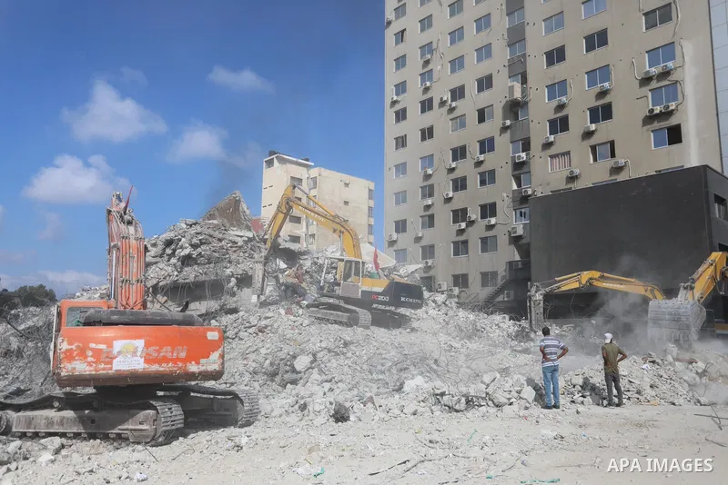 Egyptian bulldozers and Palestinian workers remove the rubbles of Jala' Tower recently destroyed by Israeli strikes in Gaza City on July 10, 2021. Gaza’s housing ministry said on that 16,800 housing units had been damage...