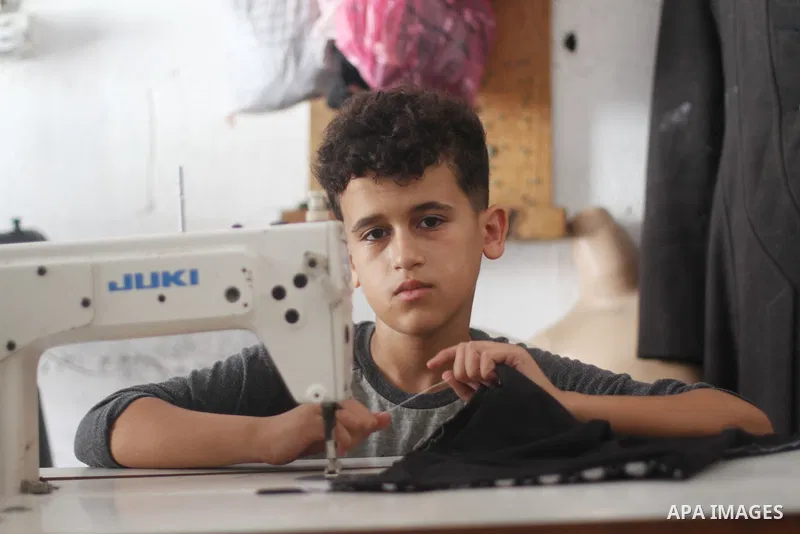 Palestinian boy Ahmed Abbas, 13, works at his father's sewing workshop at the Shati refugee camp in Gaza City, July 12, 2021. Ahmed has become the youngest tailor or fashion designer in the Gaza Strip. Abbas has mastered...