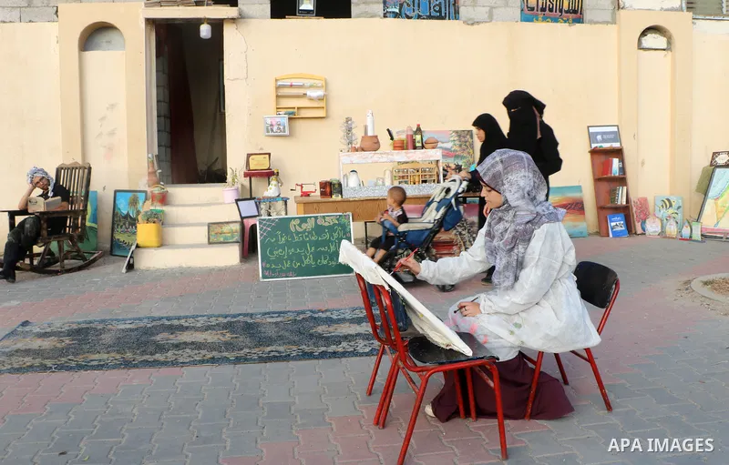 Palestinian Mohammad Saqr, 23, and Islam el-Alool, 19, set up a kiosk on the sidewalk to sell traditional foods and drinks in conjunction with practice their hobby in drawing and displaying cultural and historical books...