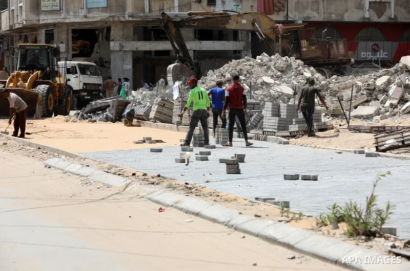 Palestinian workers work to renew a damaged road which is heavily damaged by airstrikes during an 11-day war between Gaza's Hamas rulers and Israel last May, in Gaza city, on July 24, 2021. Photo by Mahmoud Nasser