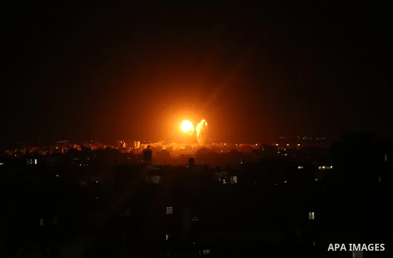 Explosions light-up the night sky above buildings in Gaza City as Israeli forces shell the Palestinian enclave, on June 17, 2021. Photo by Bashar Taleb